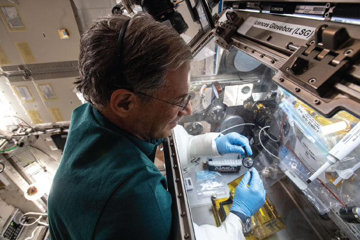 Astronaut Stibbe, aboard the International Space Station, examining the lens he fabricated in space